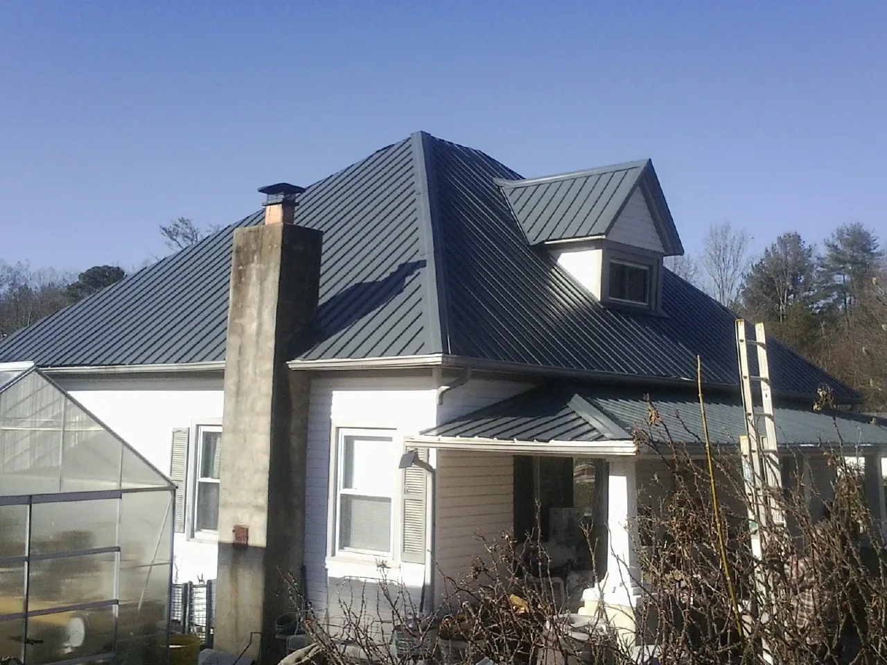 Dark blue standing seam metal roof on a white farmhouse with dormer — Slate & Tile Roof Repair by Roofing Brothers in Dalmatia