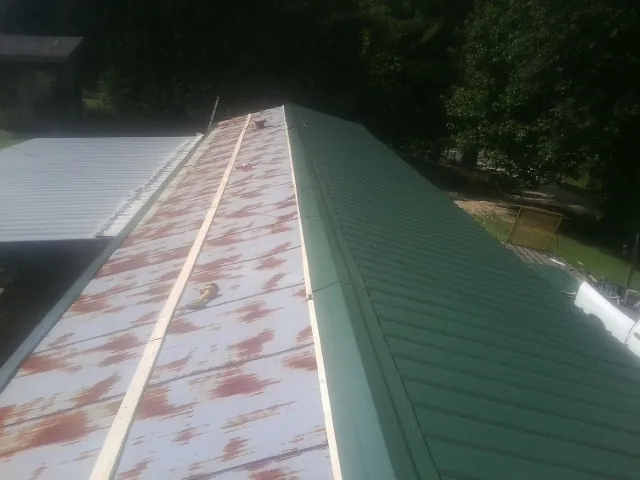 Old rusted panels beside newly installed green metal roofing — Wind Damage Roof Repair by Roofing Brothers in Dalmatia