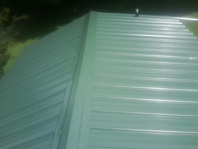 New green metal panels meeting at the ridge of a roof — Flat Roof Repair work by our crew in Dalmatia