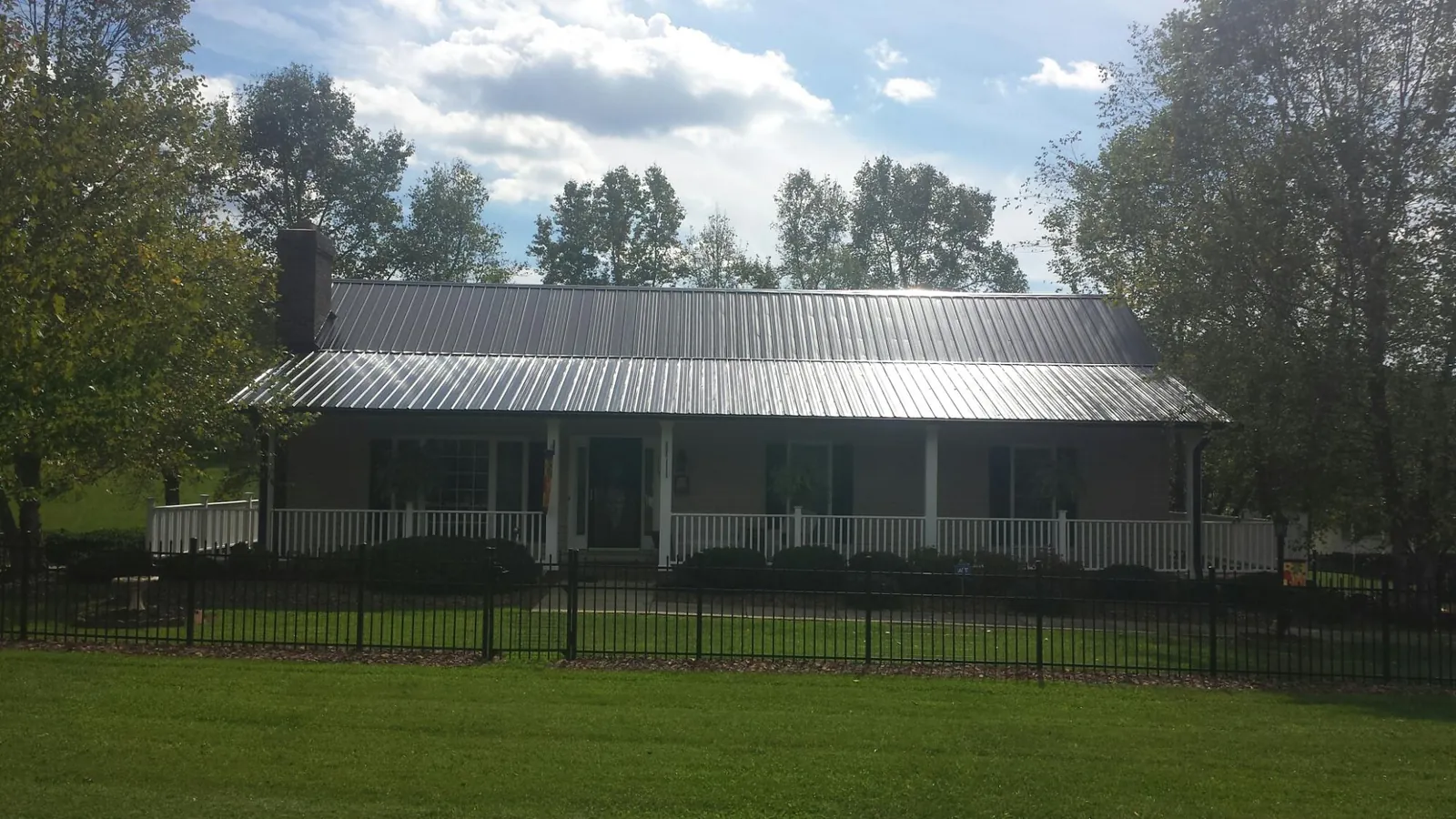 Gray metal roof on a brick ranch with a full width front porch — Gutter Guard Installation work by our crew in Dalmatia
