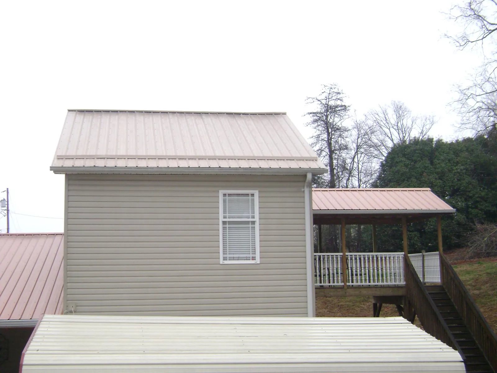 Tan metal roofs on a two story addition and attached porch, from a Roof Replacement job in Dalmatia